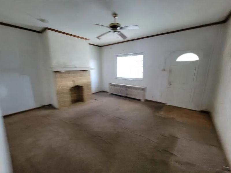 Before renovation: living room with stained carpet and a bare brick fireplace, house on 1821 Westmont Ave, Pittsburgh PA