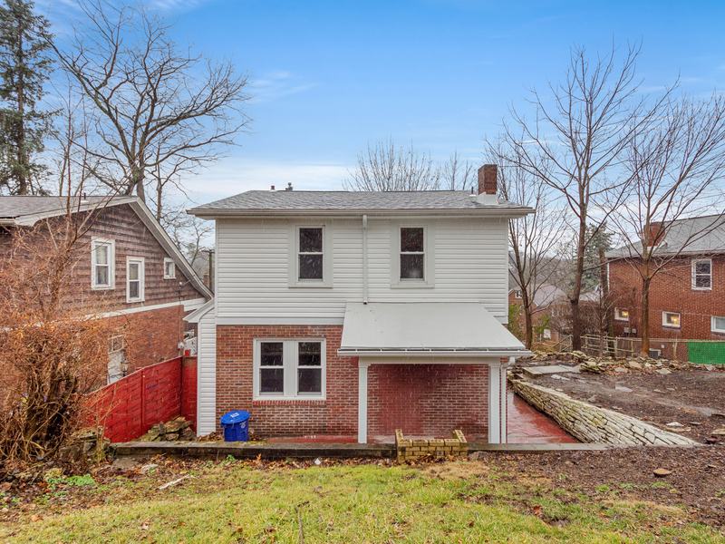 After renovation: back of the house with new white siding and a cleared yard, house on 2301 Fairland St, Pittsburgh PA