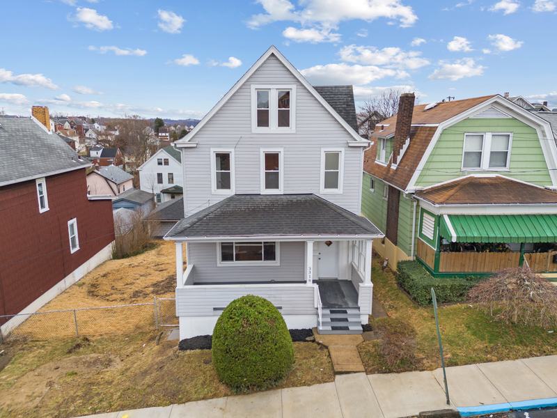 After renovation: front of the house with fresh white siding and a cleaned up yard, house on 3316 Stewart St, McKeesport PA