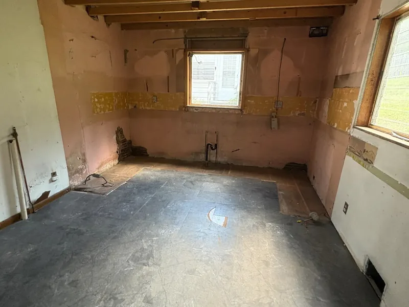 Before renovation: gutted kitchen with exposed ceiling joists and bare walls