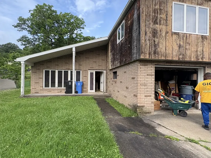 Before renovation: house with weathered wood siding and an open garage