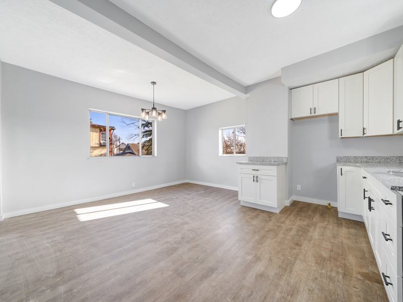 After renovation: bright open kitchen and dining room with white cabinets and new flooring, house on 705 Burbridge St, McKeesport PA