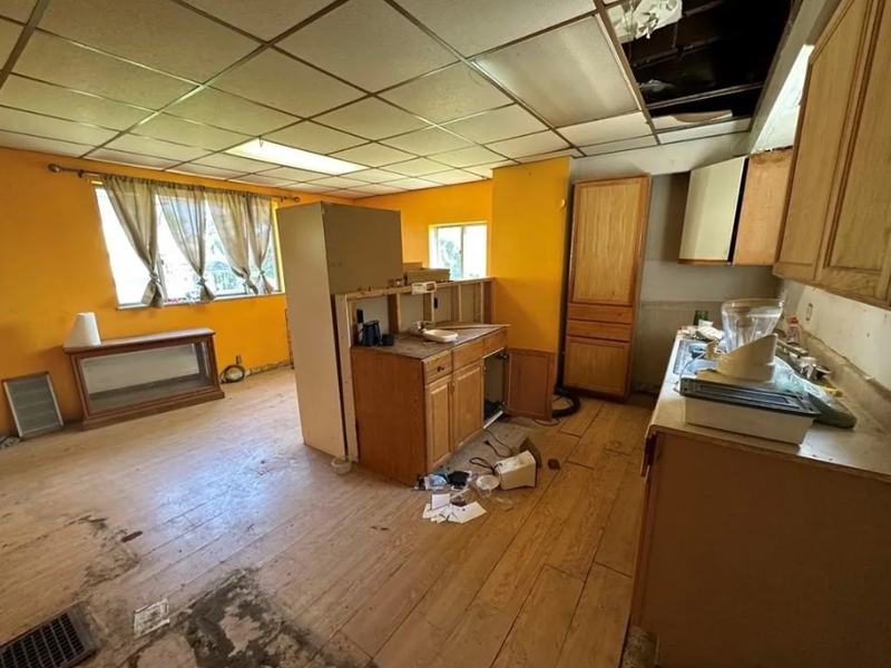 Before renovation: kitchen with orange walls, a broken drop ceiling and damaged cabinets, house on 705 Burbridge St, McKeesport PA