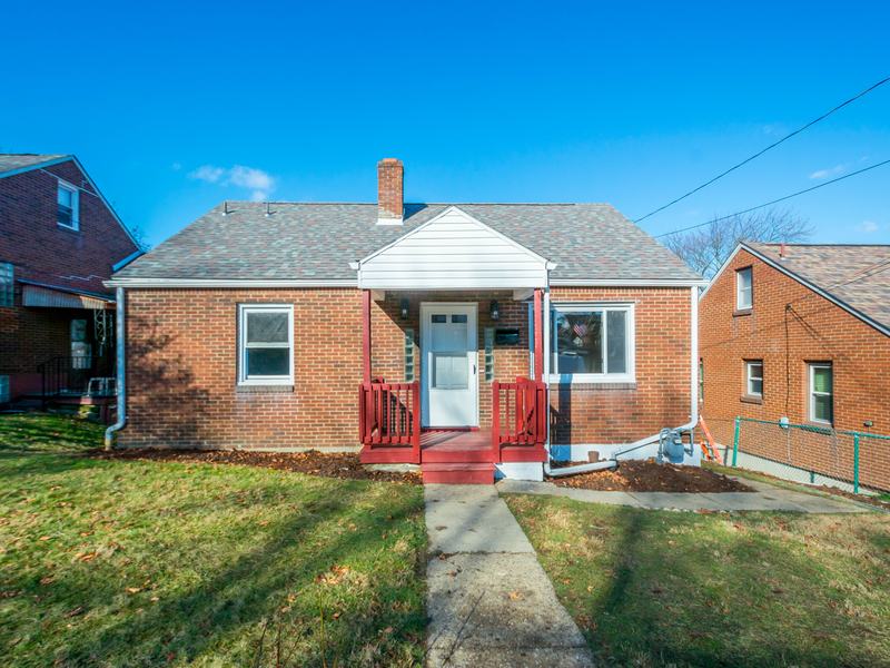 After renovation: brick house with new red porch railings and a green lawn, house on 726 Upston St, McKeesport PA