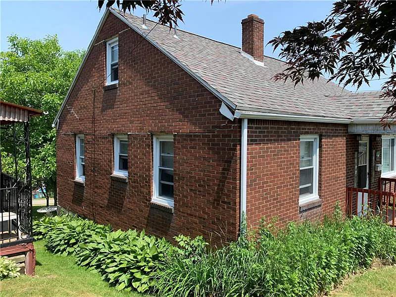 Before renovation: brick house with overgrown shrubs, house on 726 Upston St, McKeesport PA