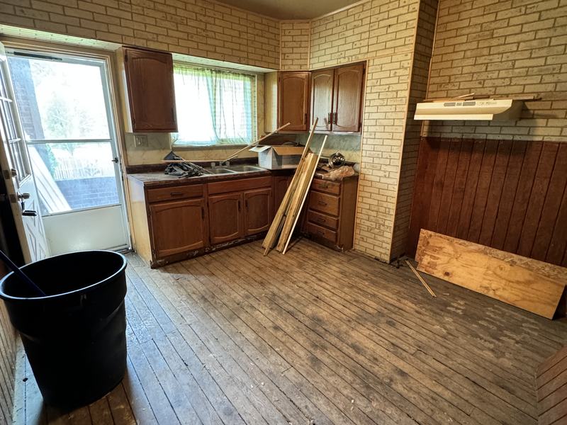 Before renovation: worn kitchen with old wood floors and painted brick walls, house on 815 Monongahela Ave, Glassport PA