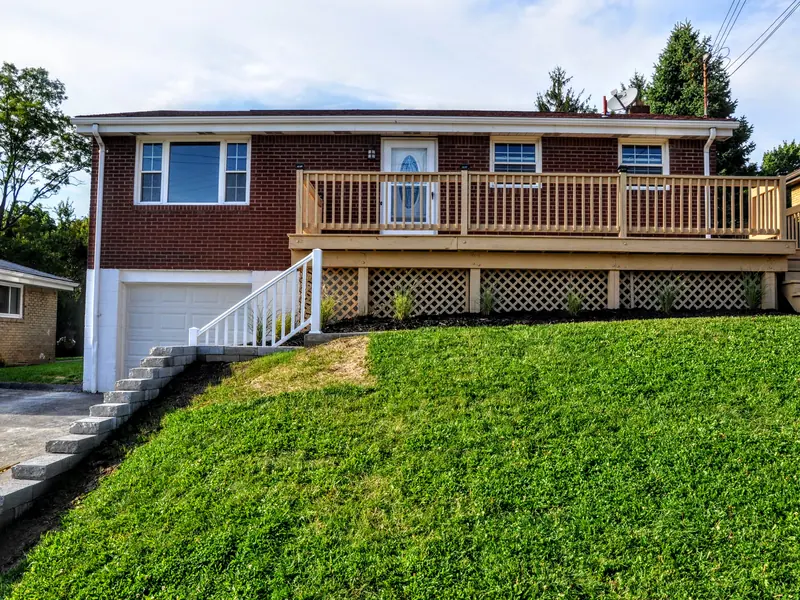 Same West Mifflin house on Joyce Dr after renovation, with a new deck, fresh siding and a green lawn