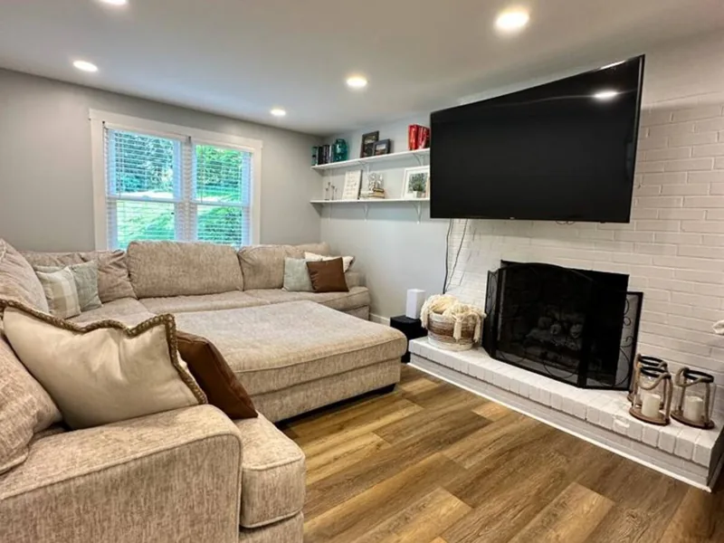 Same family room on Forest Rd in Bethel Park after renovation, with a painted brick fireplace, new floors and recessed lights