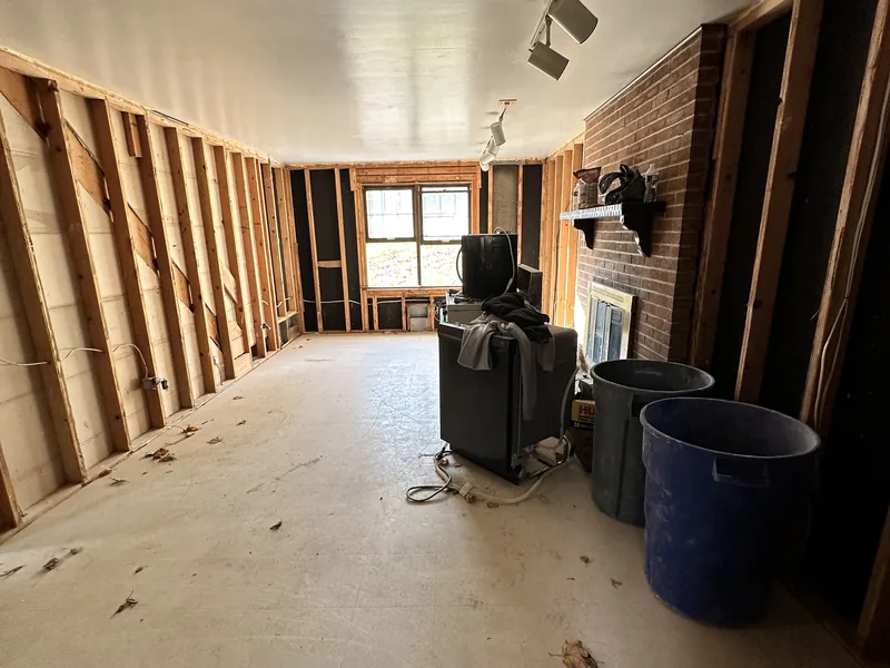Family room in a Bethel Park home on Forest Rd during renovation, stripped to the studs with a brick fireplace on the right